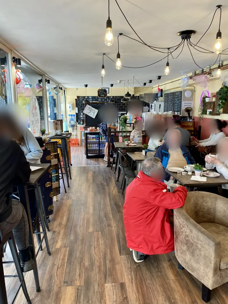 A busy morning in the café, with people chatting at tables under the festoon lights